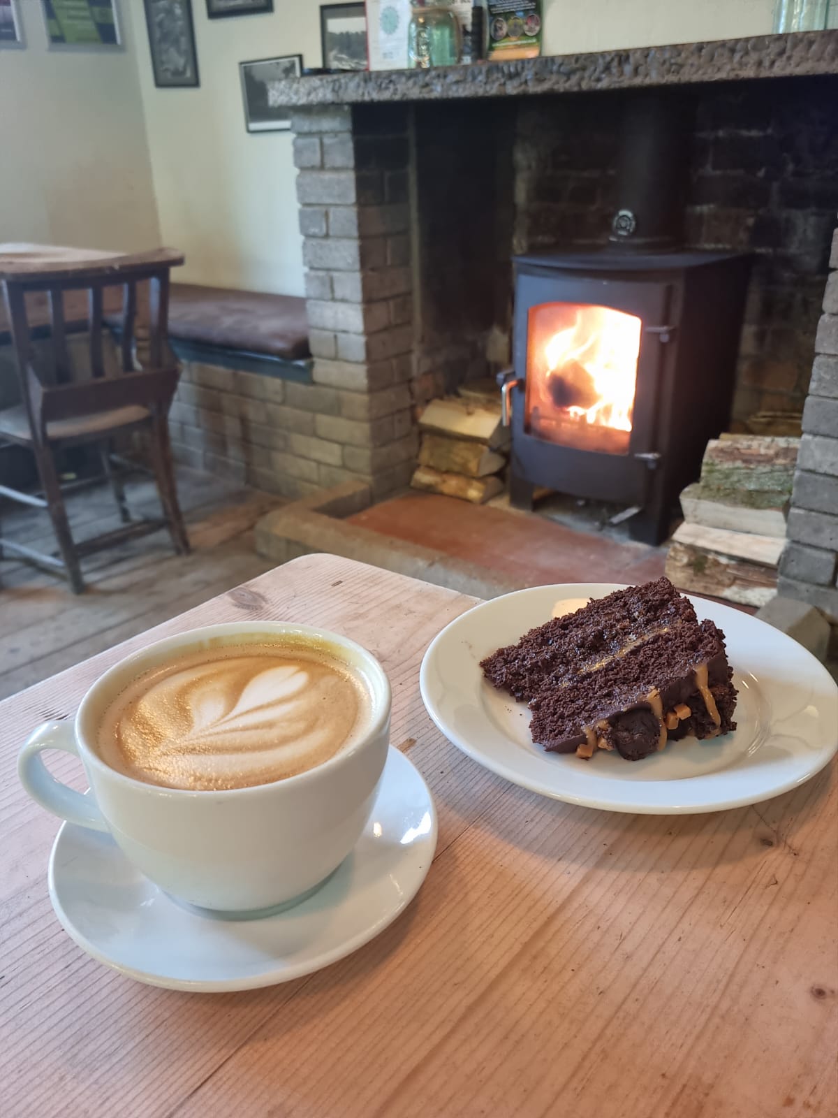Coffee and cake on table in front of wood burner lit fire