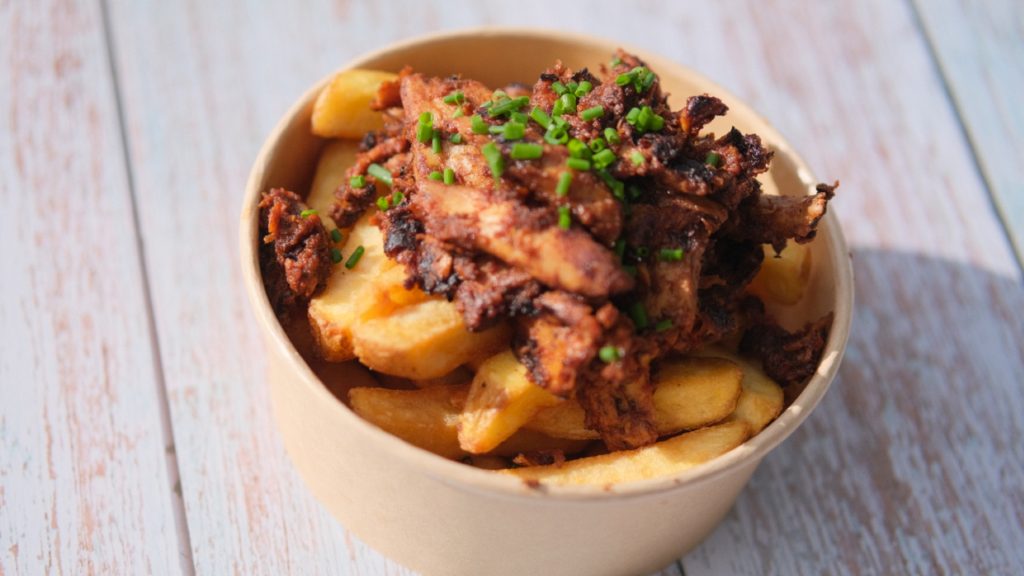 Photo of a cardboard bowl of chips topped with vegetarian pulled soya