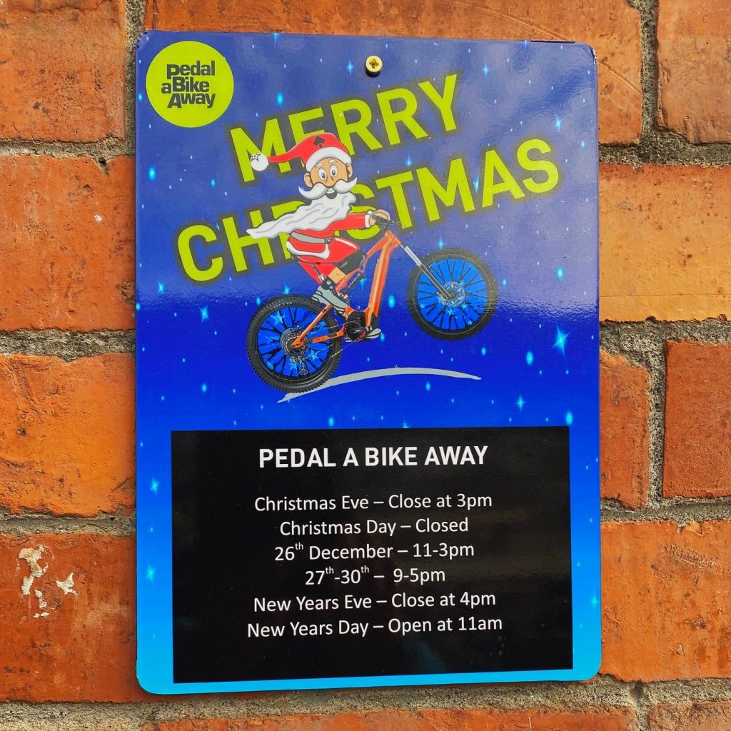 Sign displaying the Christmas opening hours at Pedalabikeaway, with a picture of Santa riding a bike