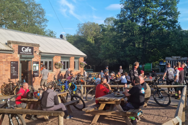 PBA Cafe exterior with lots of people eating and drinking in sunshine with mountain bikes.