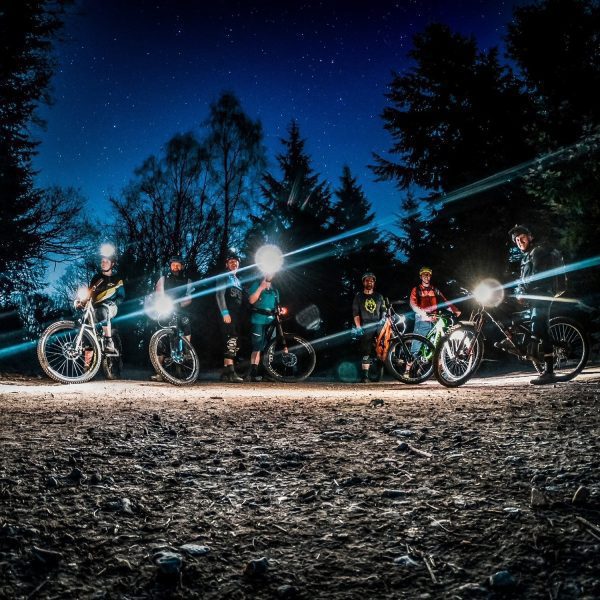 A group of mountain bike riders riding as night with torches