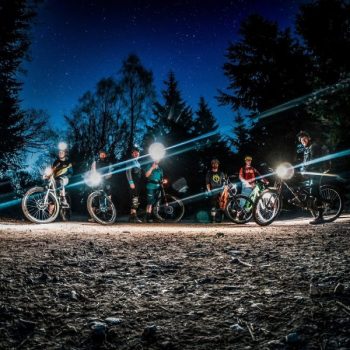 A group of mountain bike riders riding as night with torches
