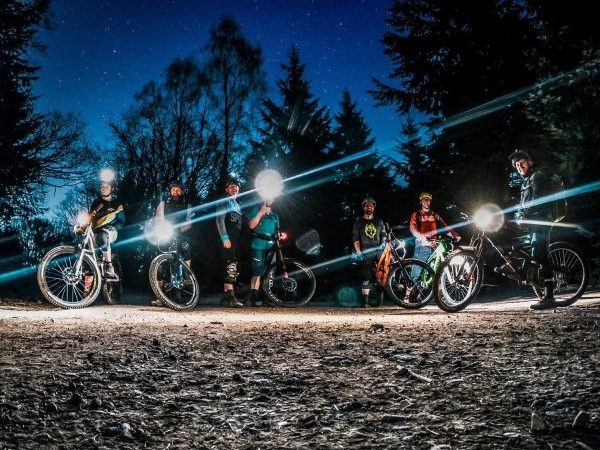 A group of mountain bike riders riding as night with torches