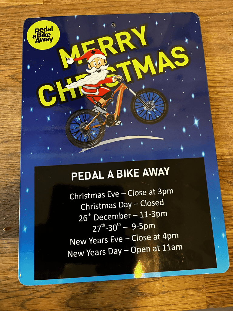 Christmas Opening Hours sign with Santa on his bike