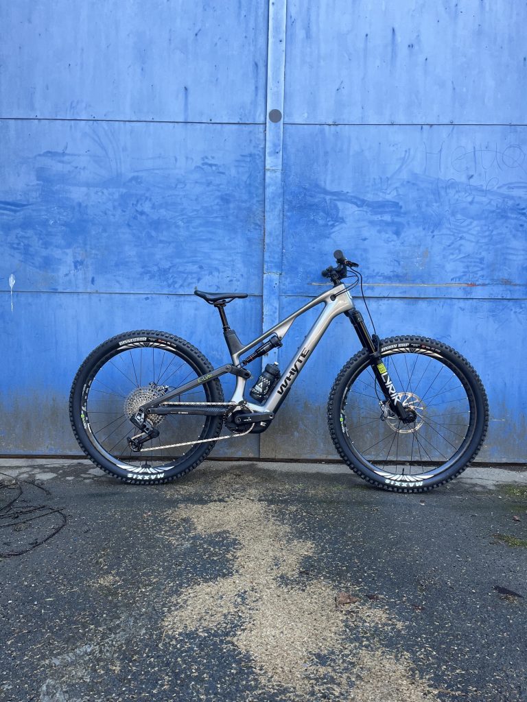 Whyte E Lyte 150 leaning against blue door