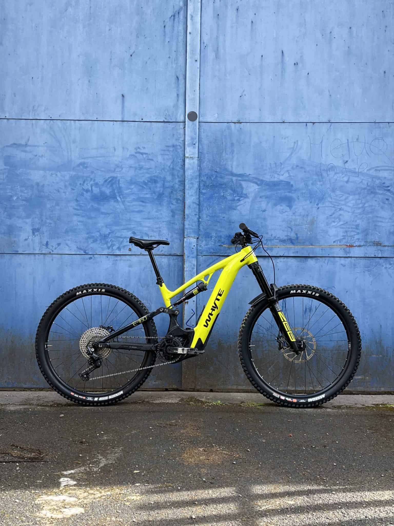 Red Whyte E-160 Full suspension e bike leaning on blue door. 
