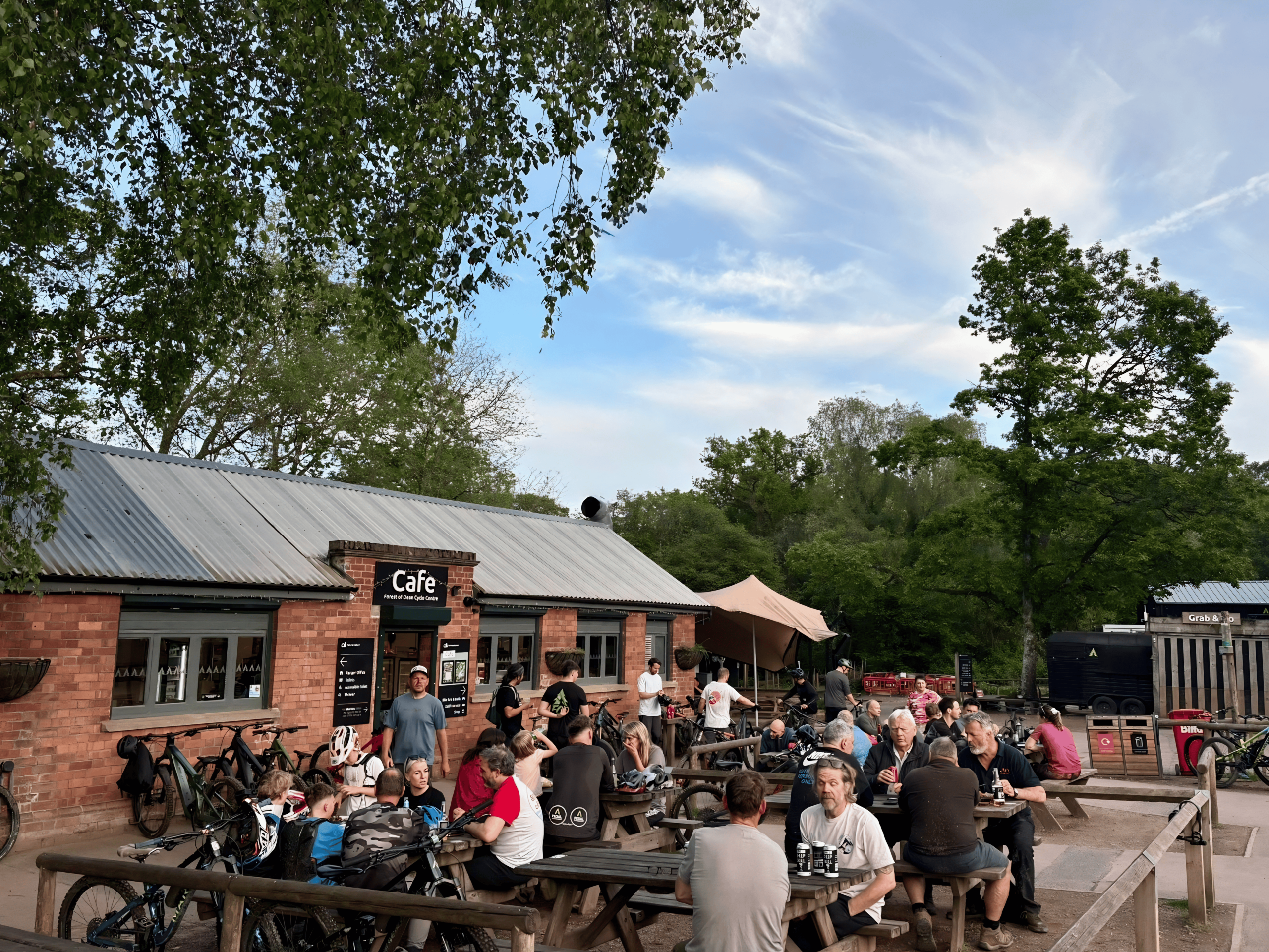 Photo of the outside of the cafe in the sunshine with people eating, drinking and chatting